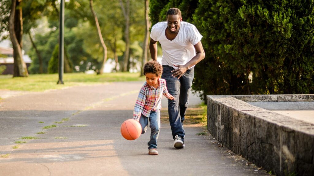 Un père et son enfant jouent au ballon dans un parc