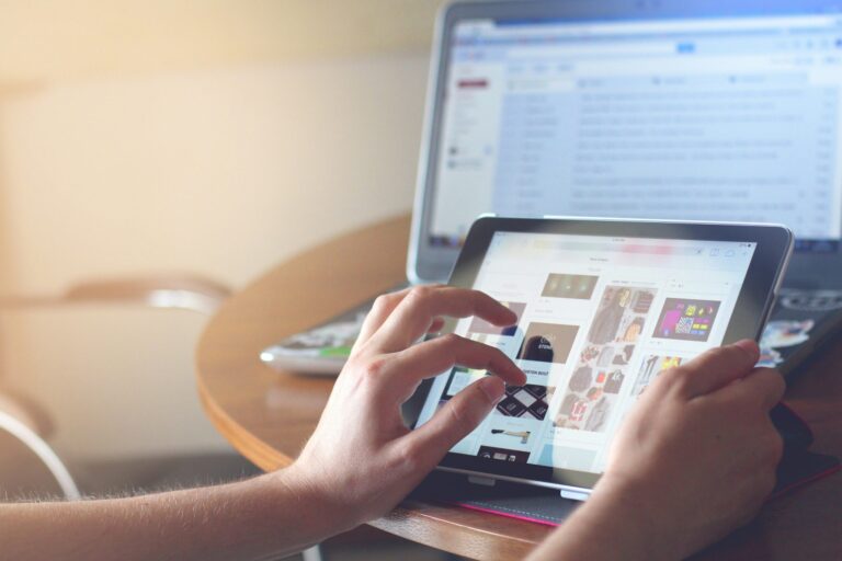 Mains utilisant une tablette devant un ordinateur portable