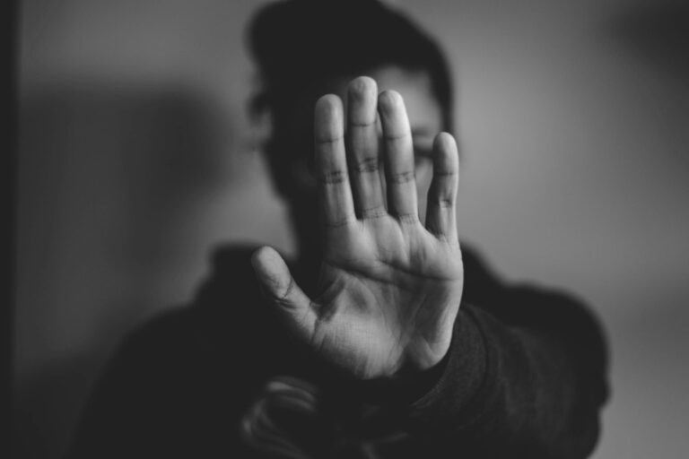 Personne tendant la main ouverte vers l’objectif en signe de refus